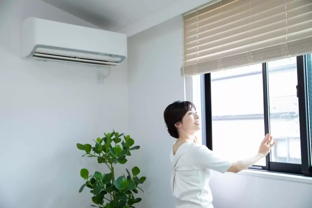 窓を開けて換気をする女性